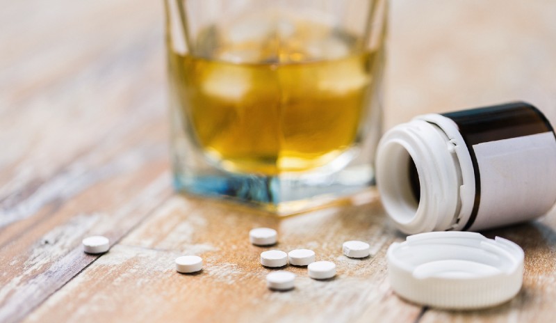 Drogenmissbrauch: ein Glas eines alkoholhaltigen Getränks und Tabletten auf einem Tisch aerzetag_am_dom_original_adobestock_syda_productions.jpg